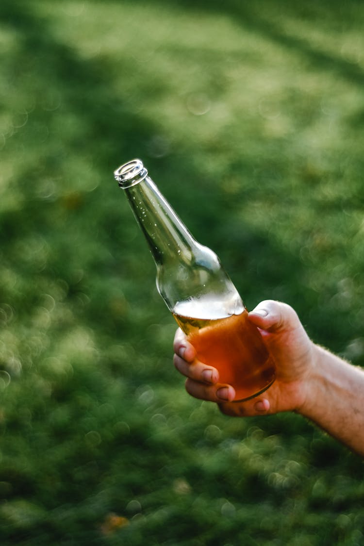 A Person Holding A Bottle Of Beer