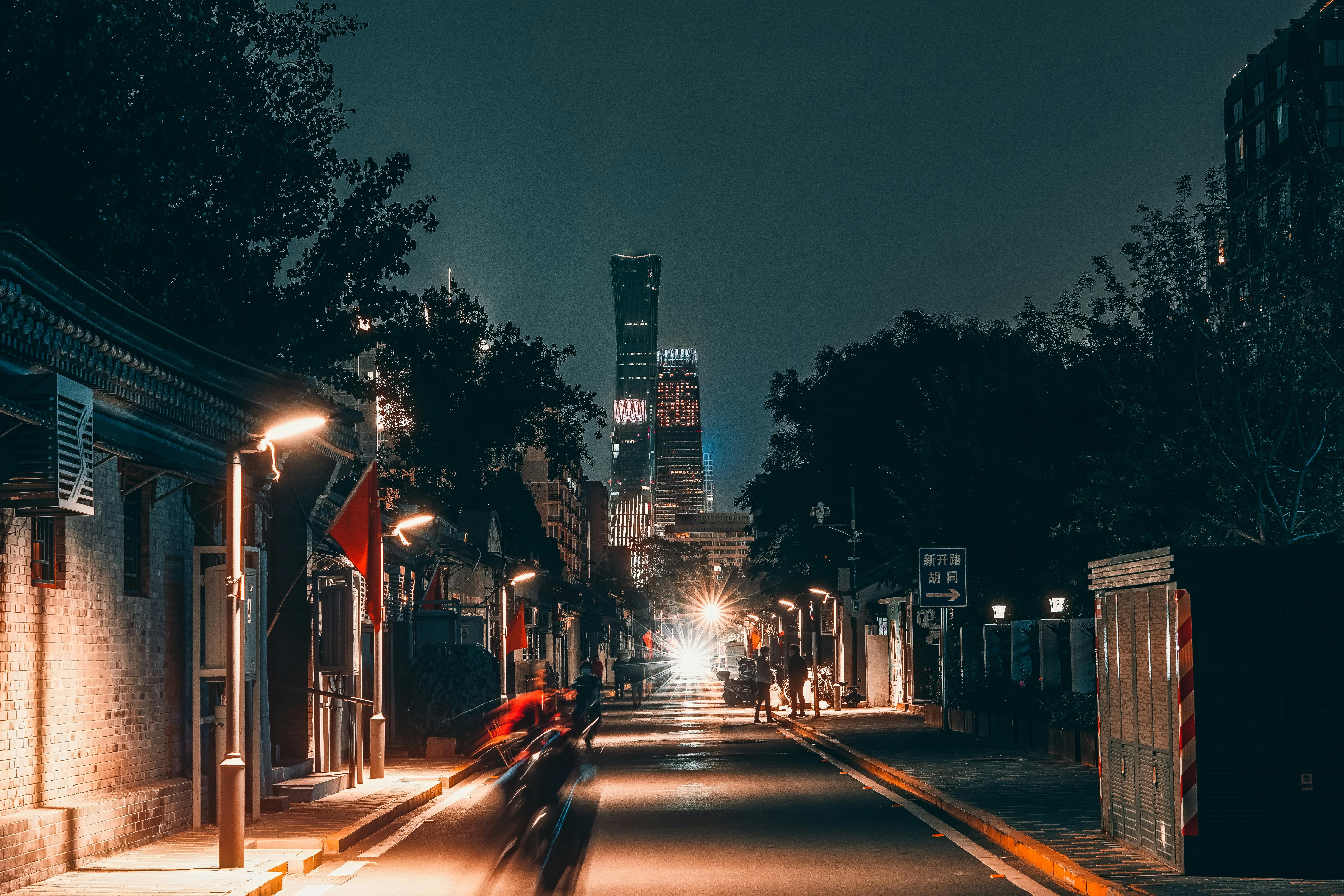 Urban street scene in Beijing at night with skyscrapers and vibrant city lights.