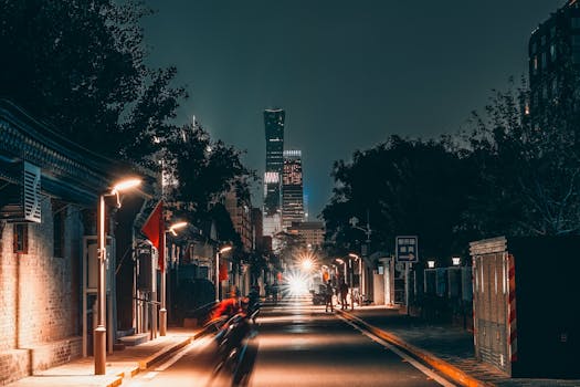 Urban street scene in Beijing at night with skyscrapers and vibrant city lights.