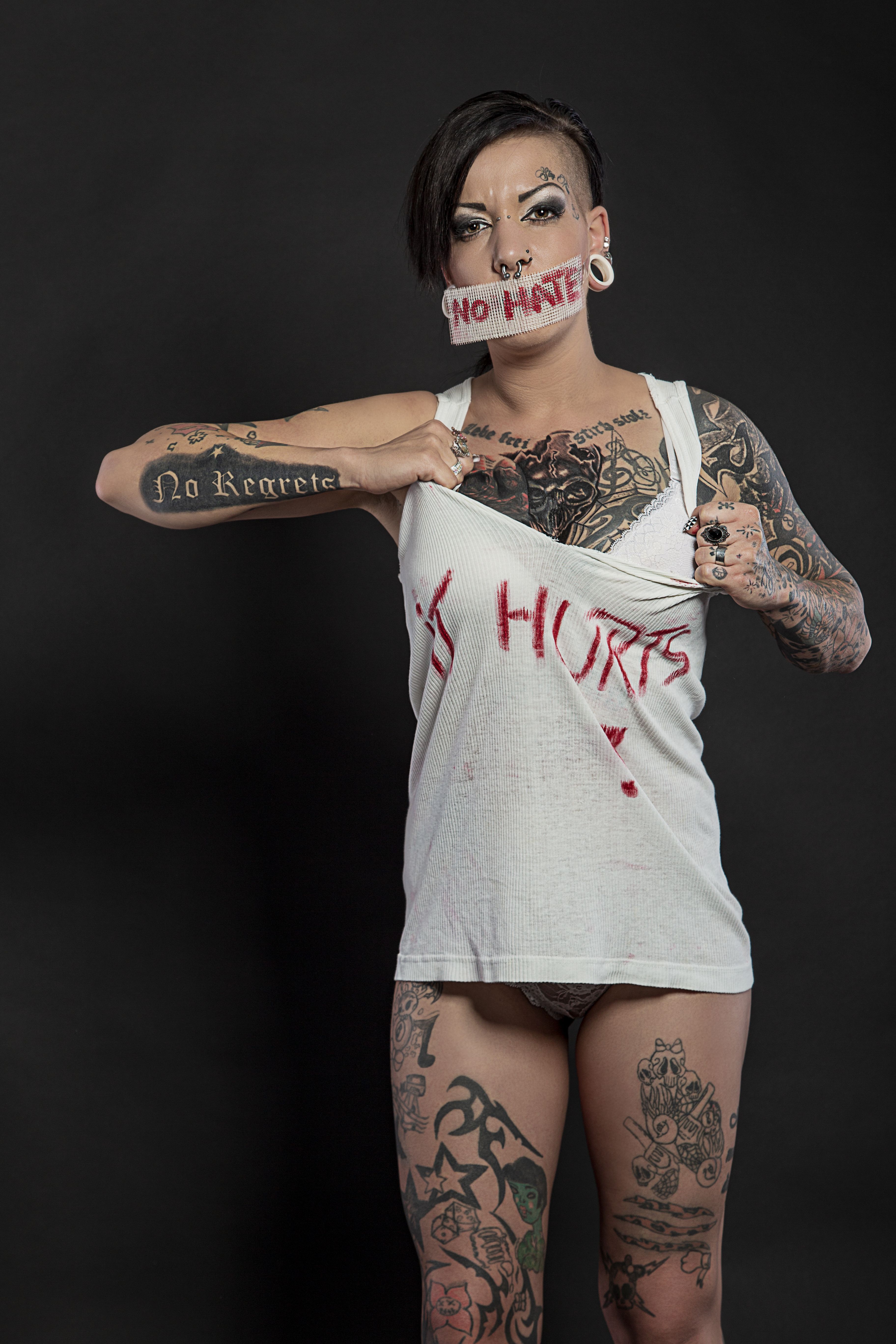Tattooed woman with 'No Hate' tape poses for a powerful statement against discrimination.