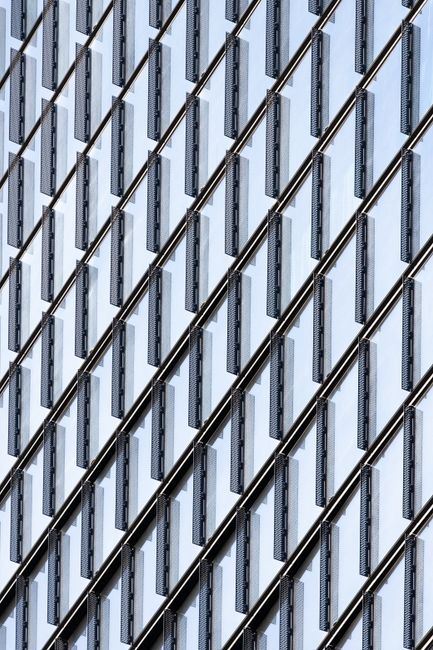 Close-up of a modern glass skyscraper facade showcasing geometric patterns and reflections.