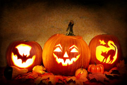 Glowing jack-o'-lanterns surrounded by autumn leaves, perfect for Halloween decor.