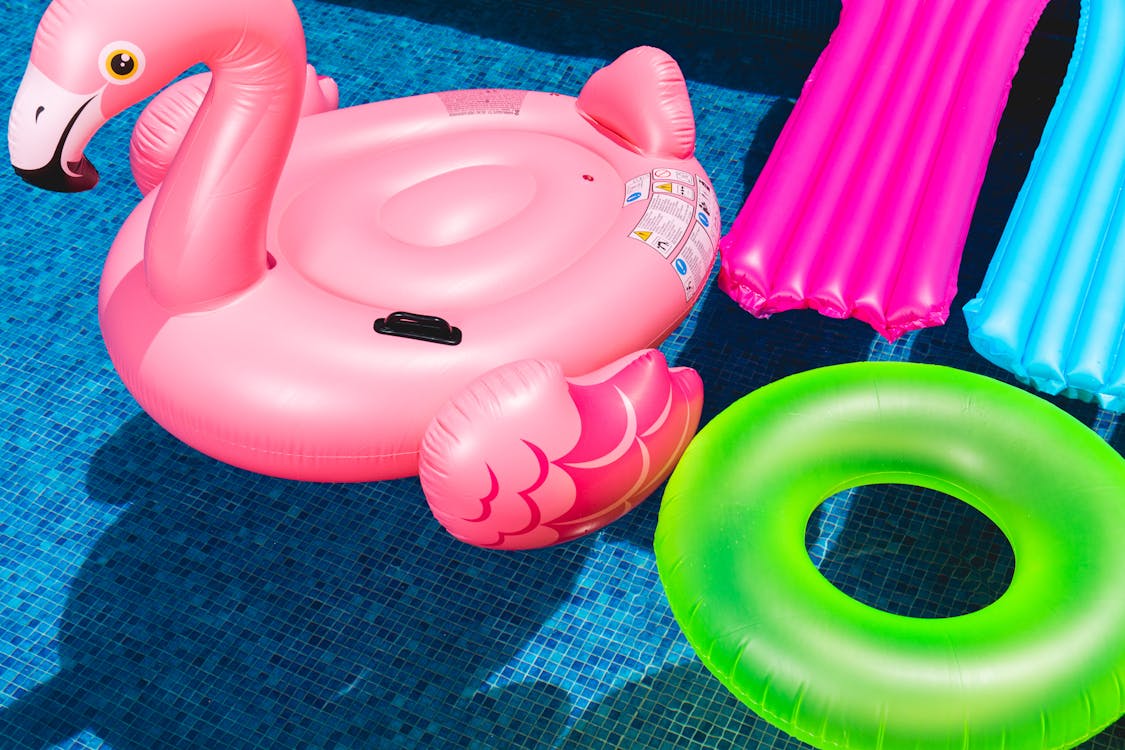 A pink flamingo float and a green ring float in a pool