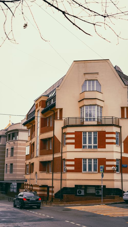 Free Charming residential street scene with modern architecture and a parked car at a corner. Stock Photo