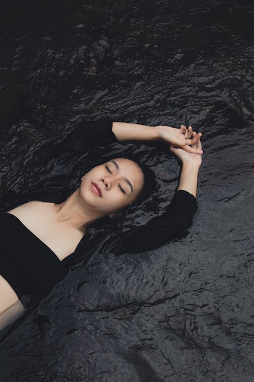 Stylish Asian teenager resting on wavy sea water