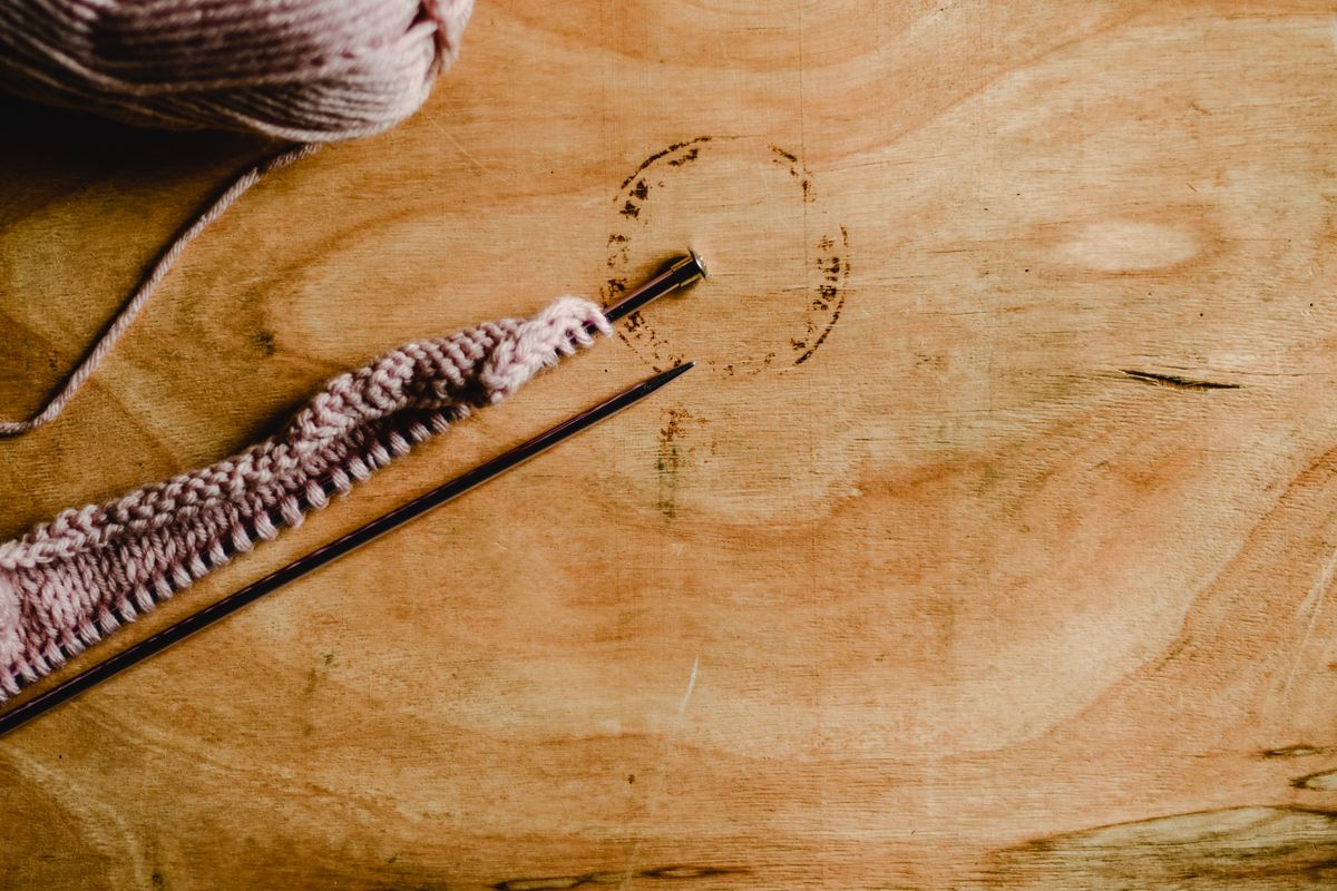 Close up of wool yarn and knitting needles on a wooden surface