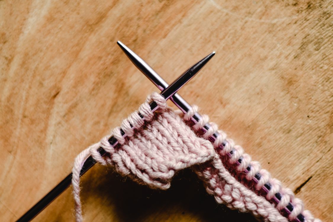 Close-Up of a Knitting Needles on a Wooden Surface · Free Stock Photo