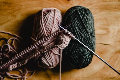 Free Detailed image of yarn rolls with knitting needles on a wooden surface, ideal for craft enthusiasts. Stock Photo