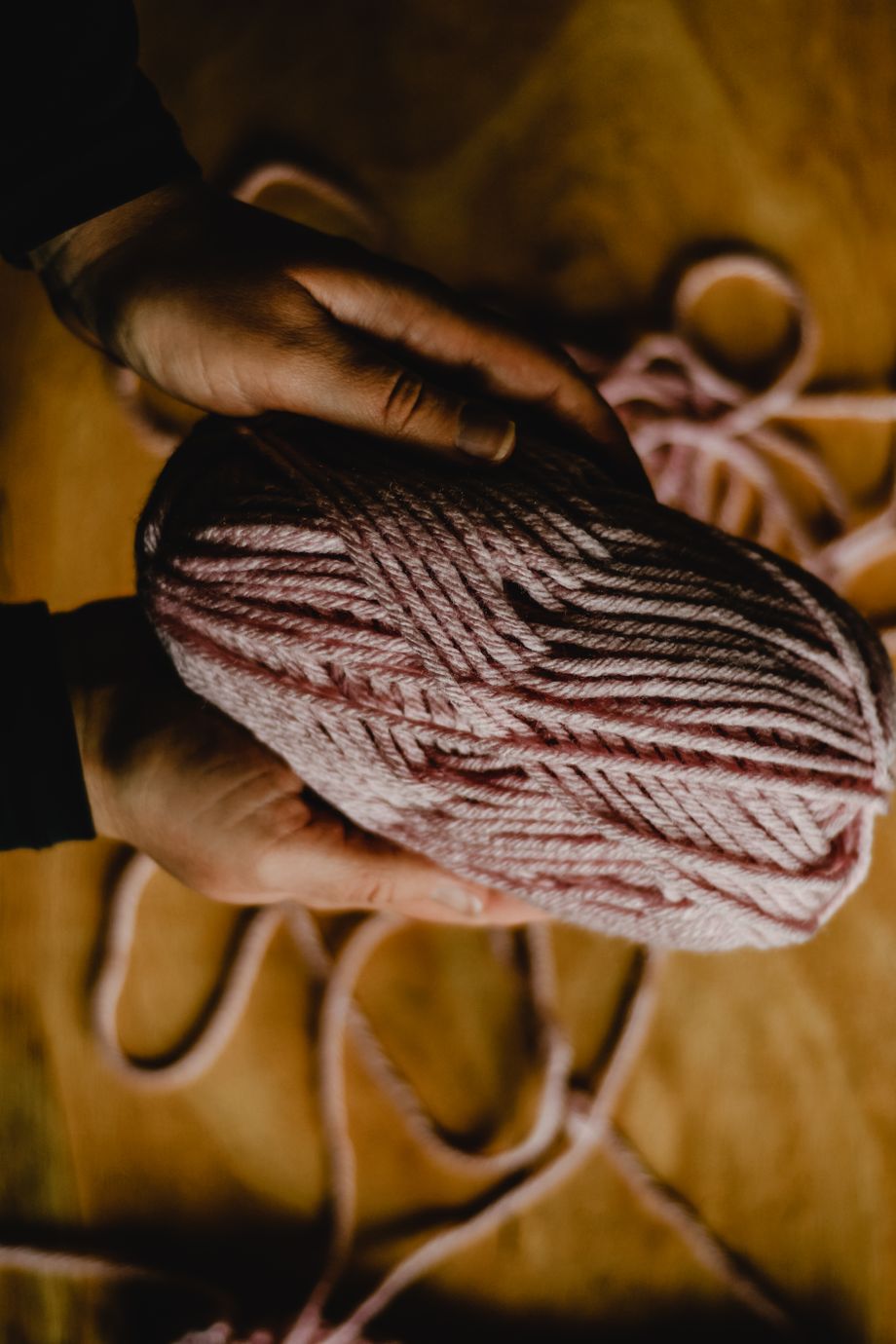 Hands cradling a skein of hand-dyed rose wool — photo by Eva Bronzini on Pexels