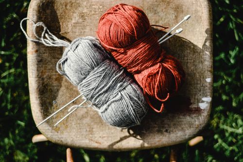 Free Close-up of vibrant yarn balls with knitting needles on a wooden chair outdoors. Stock Photo