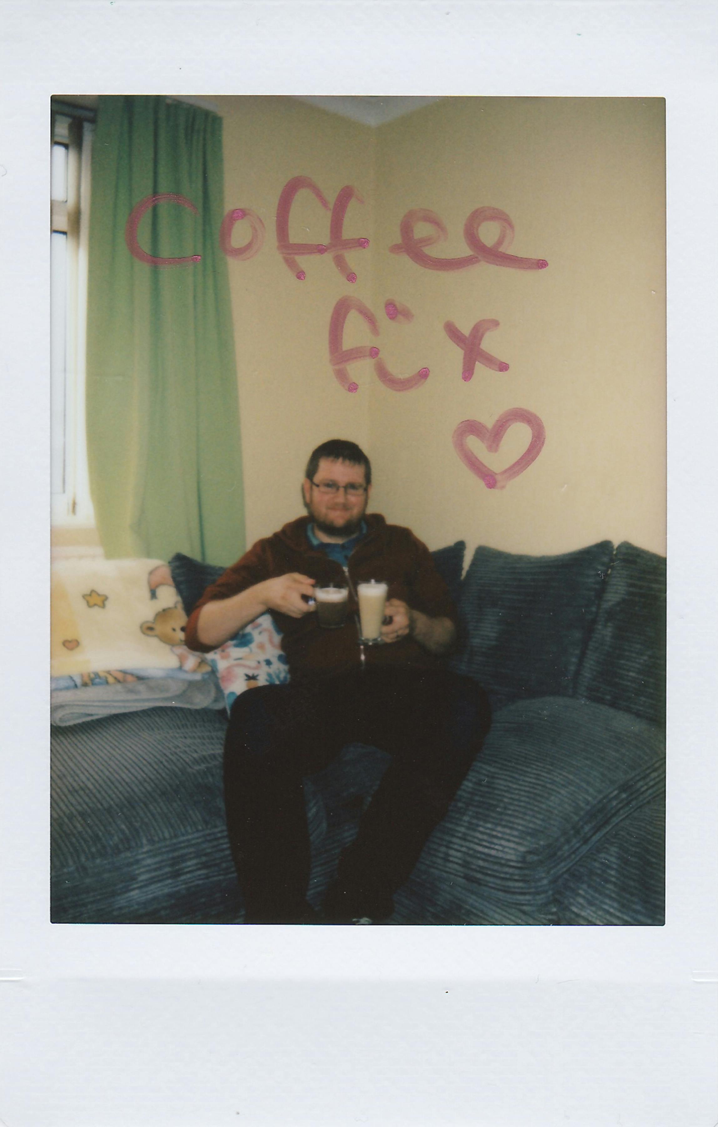 Man enjoying a coffee on a sofa with 'Coffee Fix' Polaroid effect.