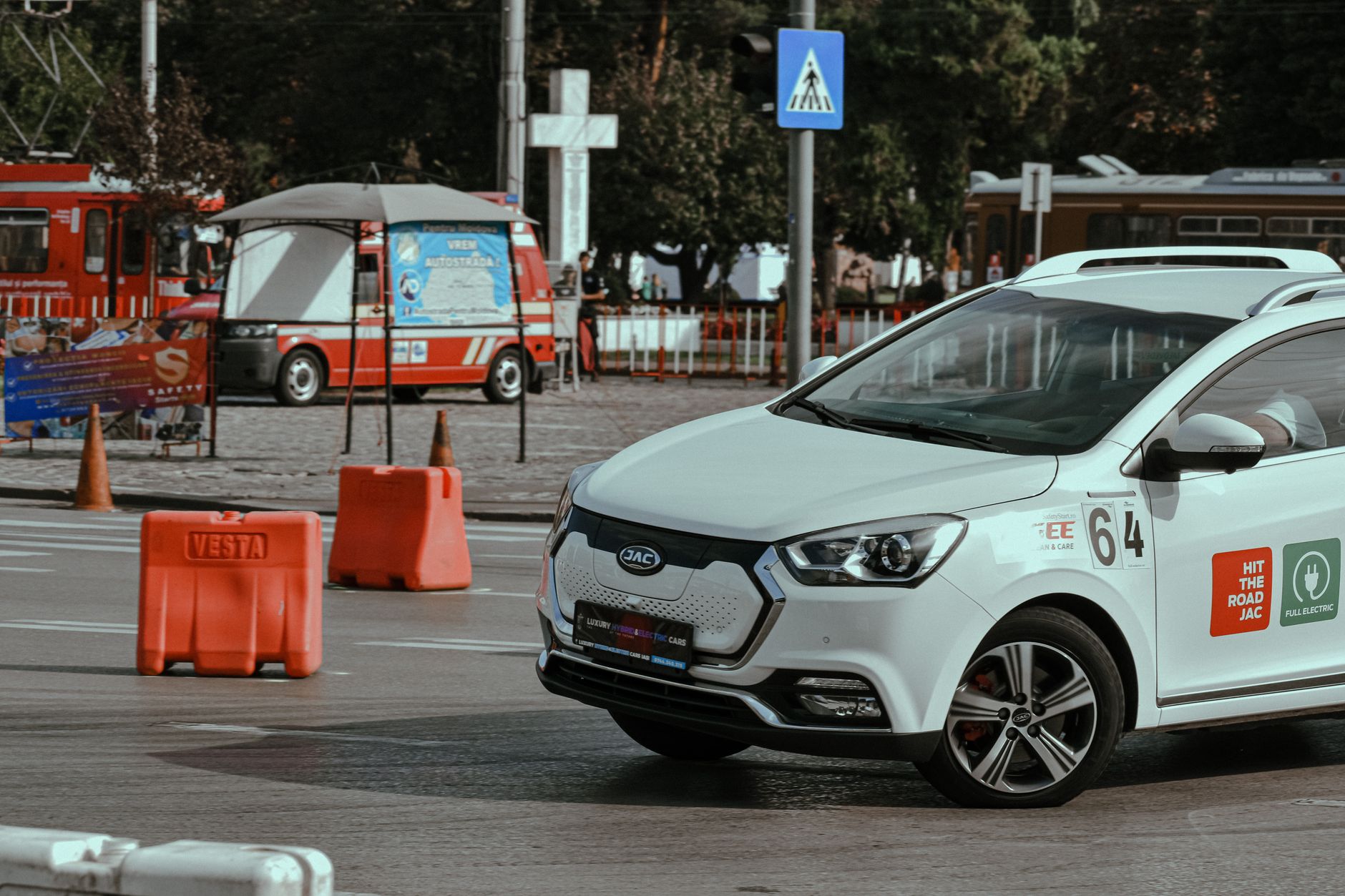 Dynamic electric car racing in a city environment with traffic cones and urban backdrop.