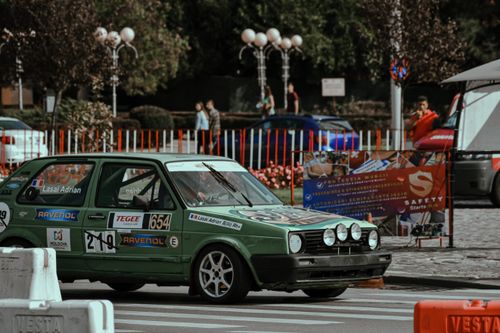 Free Green racing car in stickers driving down paved roadway in sunny city center Stock Photo