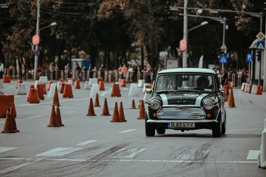 Black old timer car driving on racetrack of city street while taking part in rally