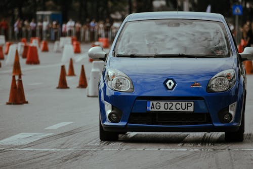 Free Modern blue automobile with headlights riding on pavement with marking lines near traffic cones on autodrome in city street with blurred background Stock Photo