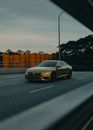 Contemporary automobile of golden color riding on asphalt roadway in suburb in twilight