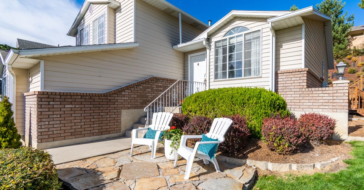 Elegant suburban house exterior with porch and seating area in bright daylight.