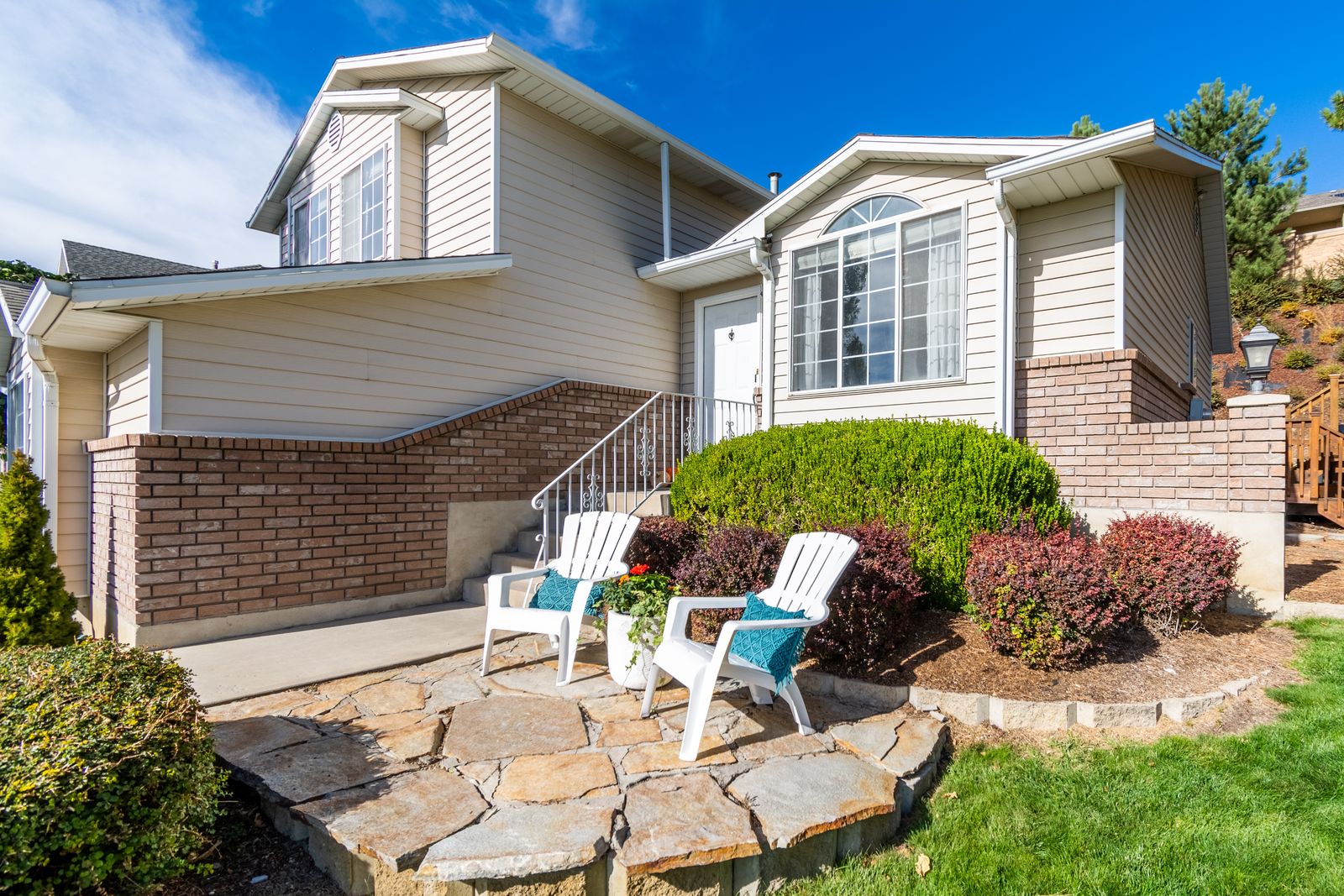 Split-level home with tan siding and a brick base, a landscaped front garden, and a flagstone patio under a clear blue sky, Signal Point, Naperville IL