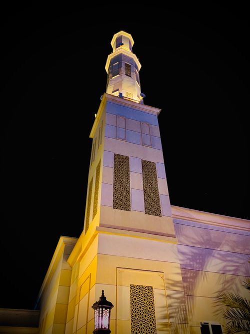 Free A beautifully illuminated minaret towering against a clear night sky, showcasing intricate architecture. Stock Photo