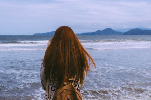 Free Back View of a Redheaded Woman Standing on a Beach Stock Photo