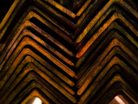Close-up of rusty steel beams arranged in a geometric pattern, showcasing industrial texture.