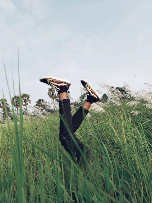 Capture of legs playfully sticking out in a grassy field with a vivid sky backdrop.