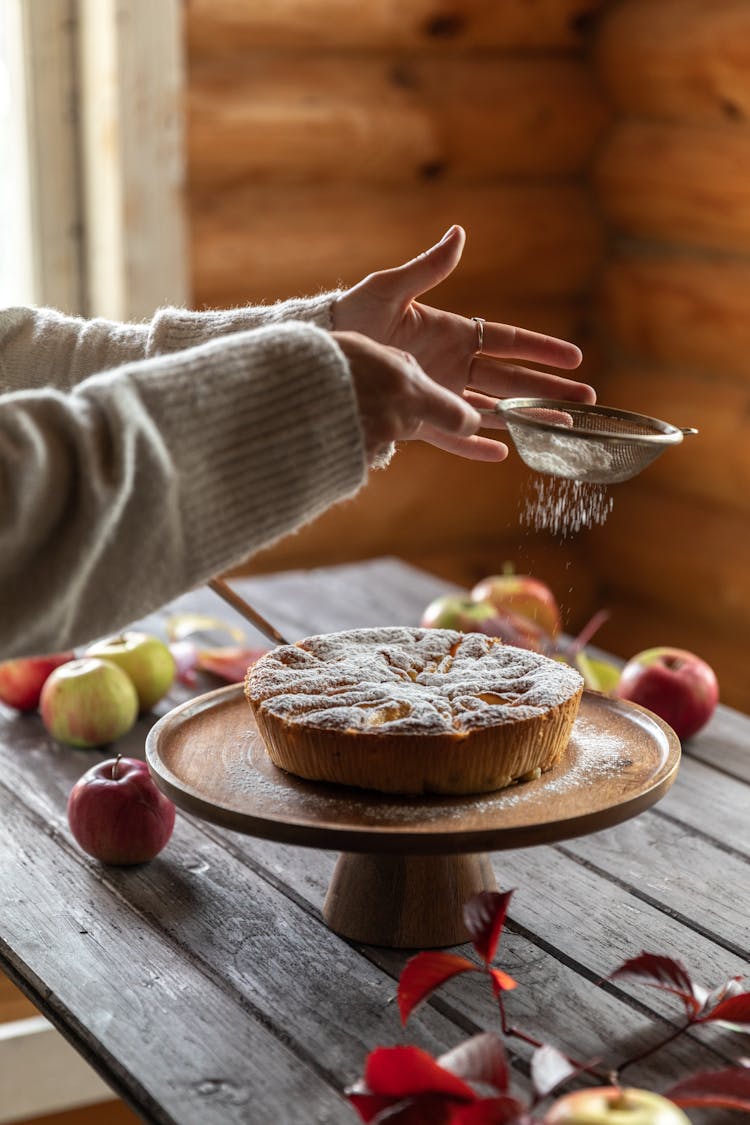 
A Person Dusting Powdered Sugar On A Pastry