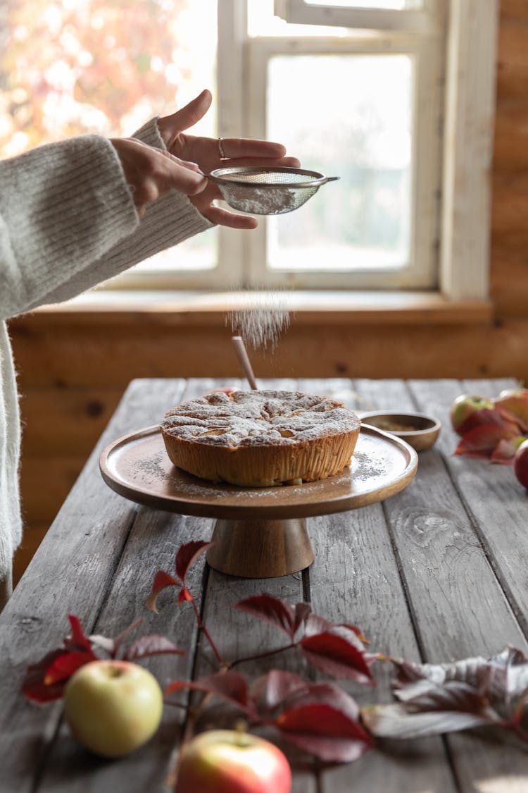 
A Person Dusting Powdered Sugar On A Pastry