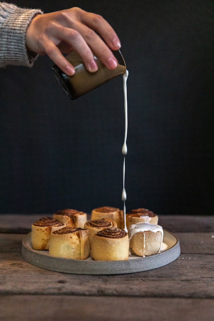 Person Pouring White Cream On Bread 