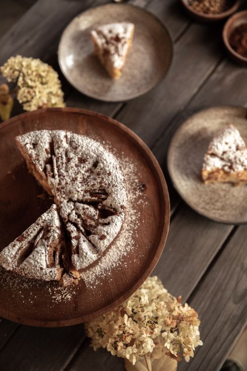 Free Delicious homemade apple cake with powdered sugar on a wooden table, perfect for dessert lovers. Stock Photo