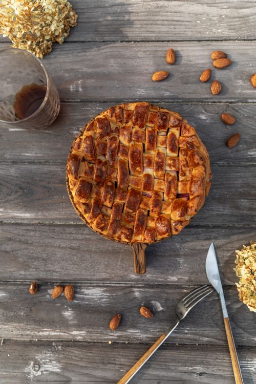Free A homemade apple pie with a lattice crust on a rustic wood table, surrounded by almonds. Stock Photo