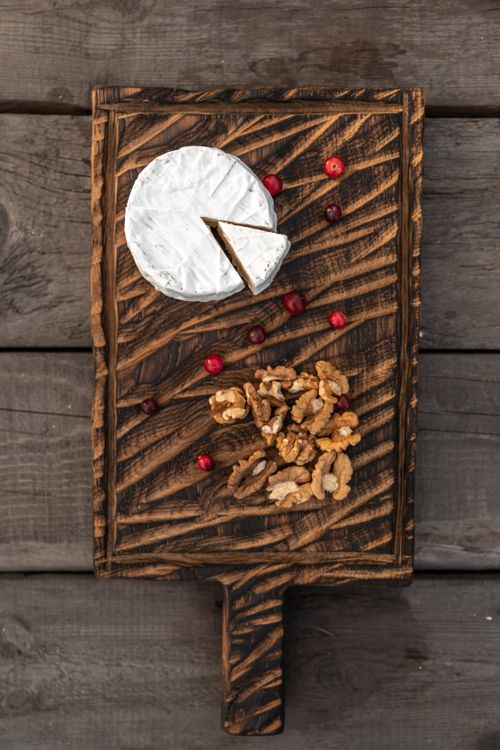 Free Top view of Brie cheese and walnuts on a wooden board with cranberries, perfect for gourmet food presentations. Stock Photo