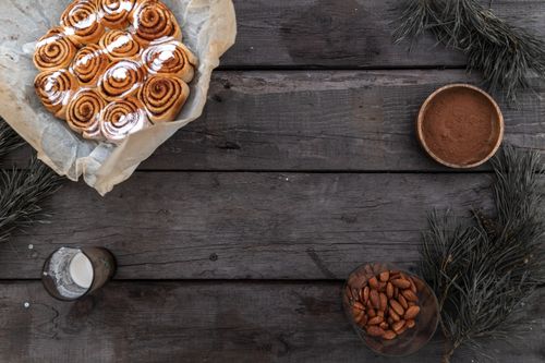 Free A top view of freshly baked cinnamon rolls with cocoa and almonds on a rustic table. Stock Photo