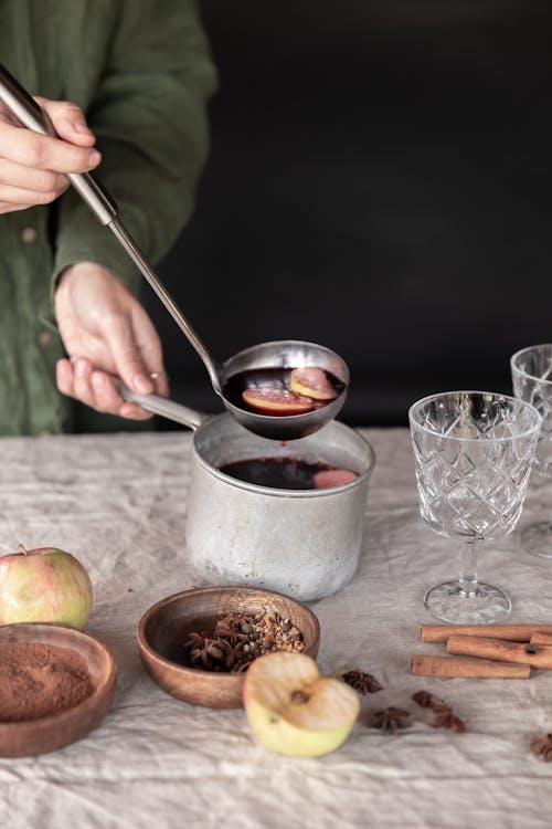 Person Holding a Stainless Steel Saucepan with Red Liquid 