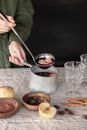 Person Holding a Stainless Steel Saucepan with Red Liquid