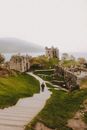 Anonymous tourist on stairs contemplating old ruined castle on mount