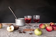 Cozy autumn setup with apples, cinnamon, and mulled wine in elegant glasses.