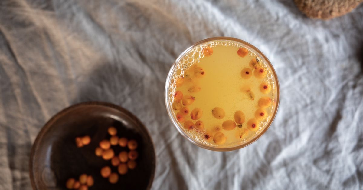 A refreshing glass of yellow sea buckthorn tea with a wooden bowl, shot from above on a textured linen background. - Evidence evidence guide for sea buckthorn cholesterol meta-analysis