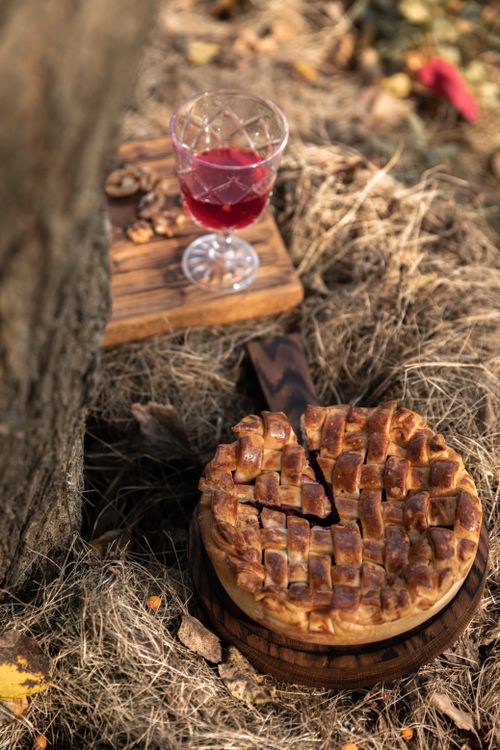 Free A rustic apple pie complemented by a glass of red wine in an outdoor autumn setting. Stock Photo