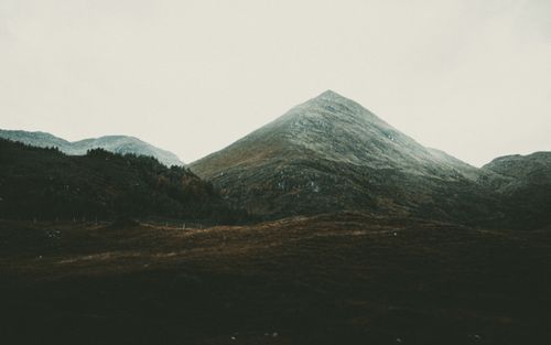 Free Mountain ridge covered with snow located behind valley with trees on cloudy weather Stock Photo