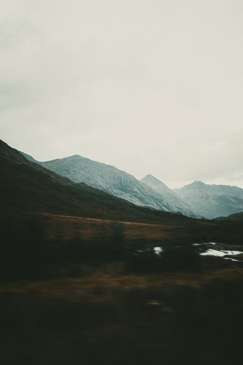 Free Valley of cold dark fields with ridge of mountains under gloomy foggy sky Stock Photo