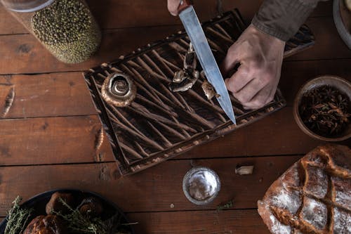 Free Person Holding a Knife Slicing Mushrooms on Wooden Chopping Board  Stock Photo