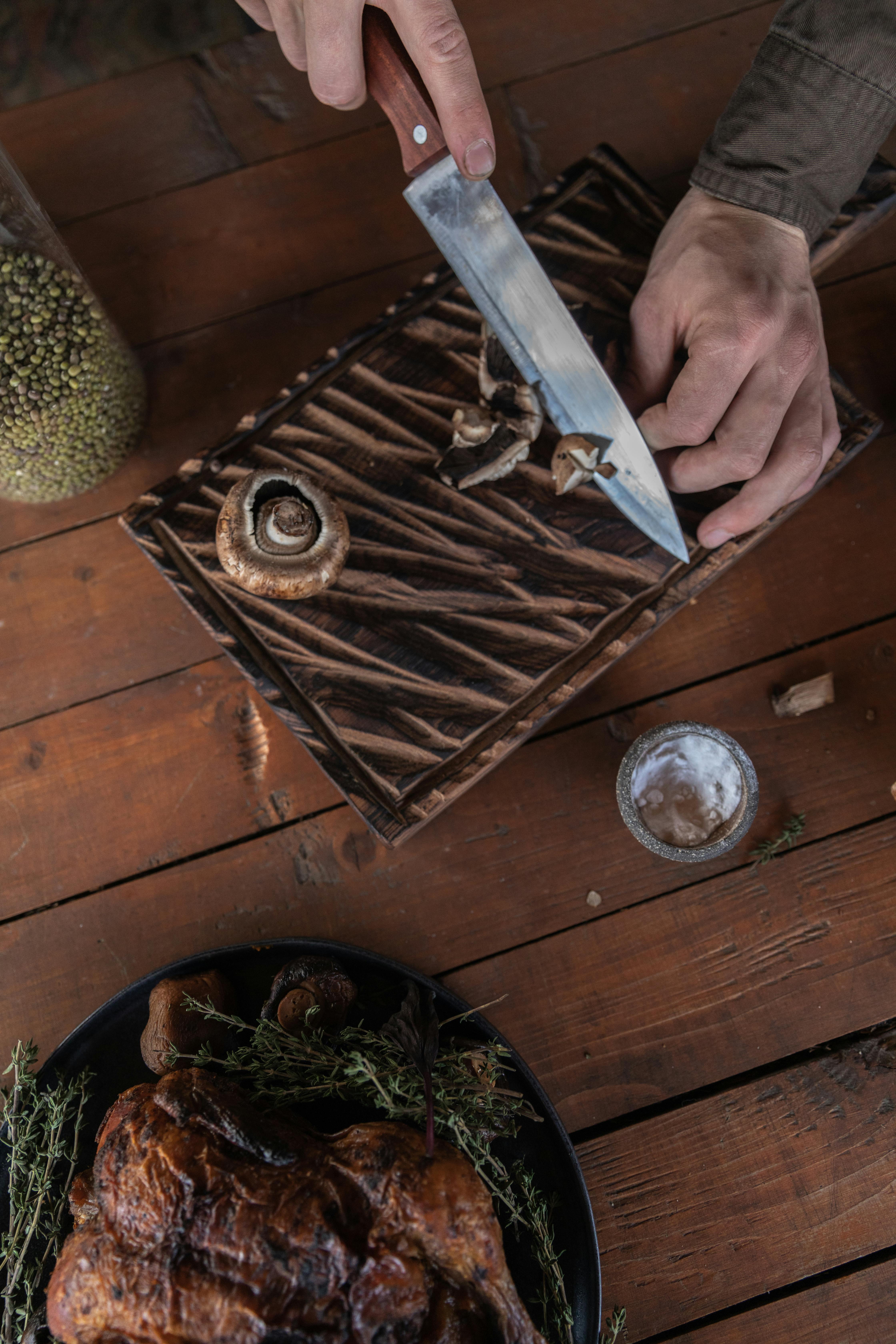 person holding knife slicing a mushroom