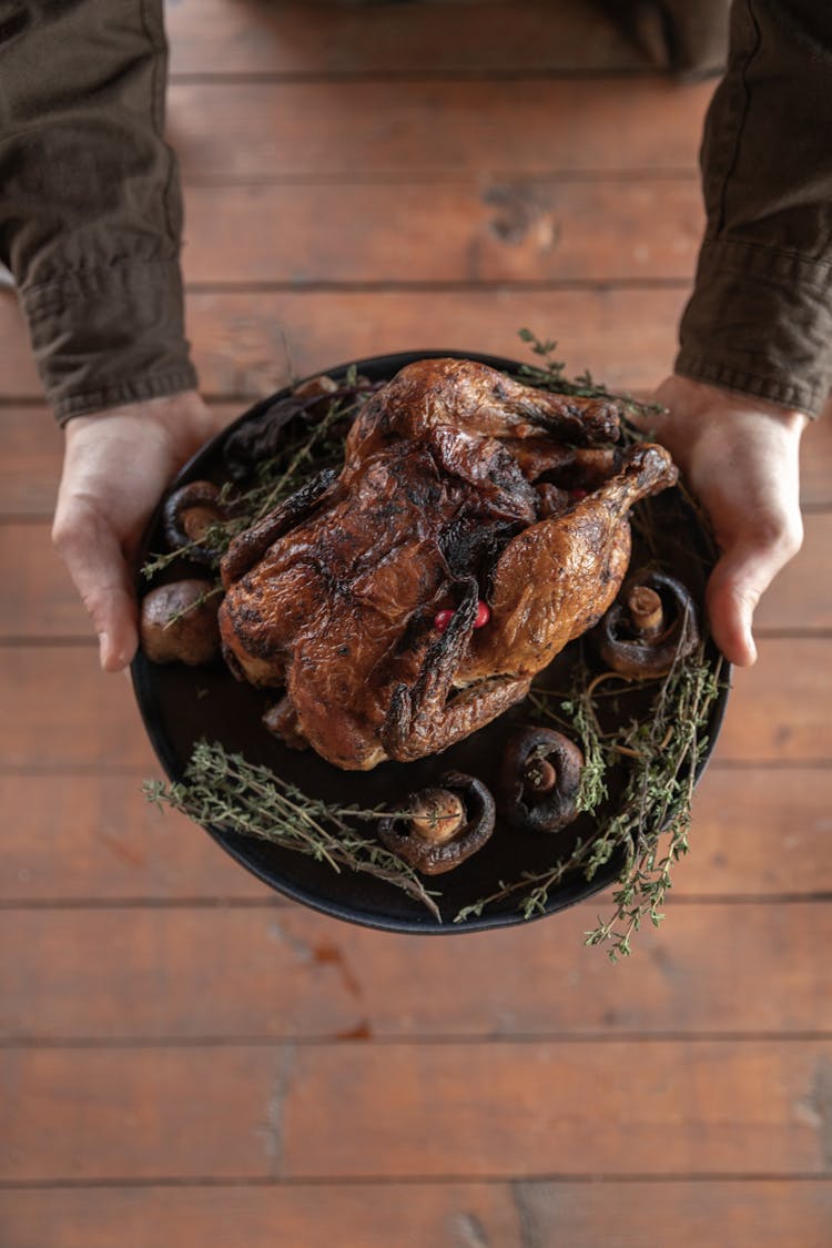 Person Holding Black Round Plate With Cooked Turkey