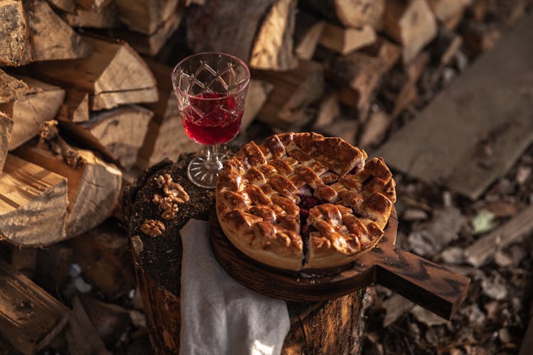 A Baked Pie And A Glass Of Drink On A Tree Stump