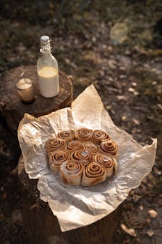Warm and delicious cinnamon rolls on parchment with a bottle of milk outdoors.