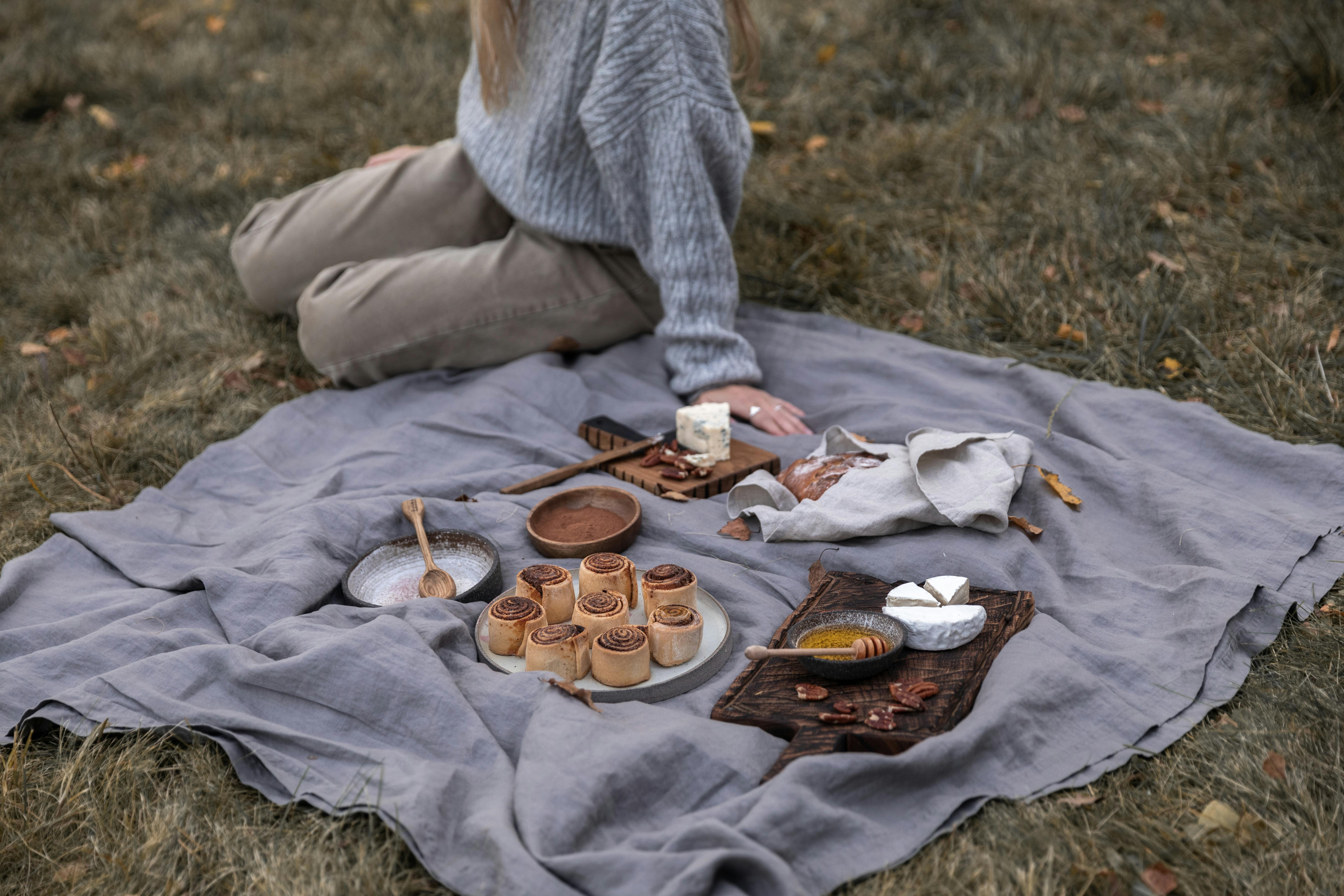 Serene autumn picnic featuring cheese, pastries, and a cozy blanket setup in the outdoors.