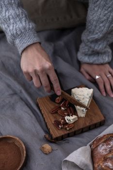 手工在木板上切片奶酪和坚果的温馨场景，非常适合食品主题