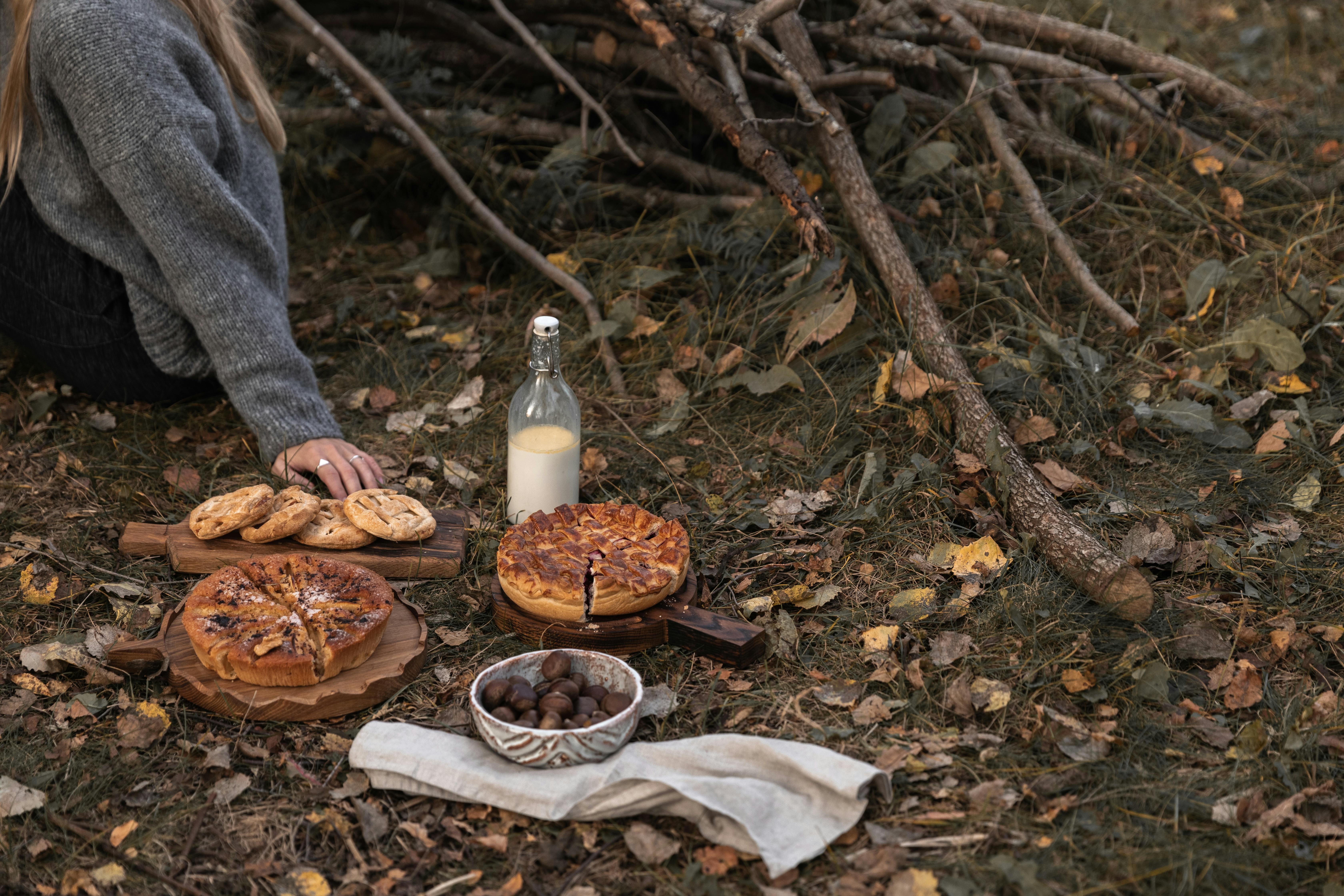 A cozy autumn picnic with pies, milk, and pastries on a forest floor.