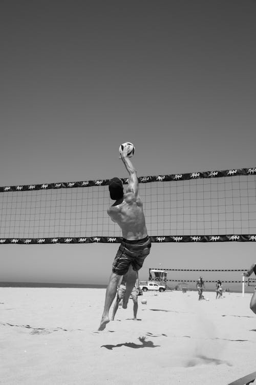 Grayscale Photo of a Man Playing Beach Volleyball